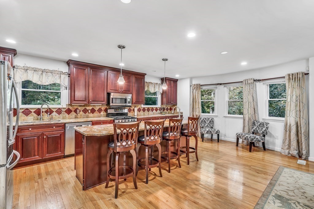 3 Goodnow Road Sudbury, MA 01776 - Photo 7 of 34 a kitchen with stainless steel appliances granite countertop a stove top oven a sink dishwasher and a dining table with wooden floor