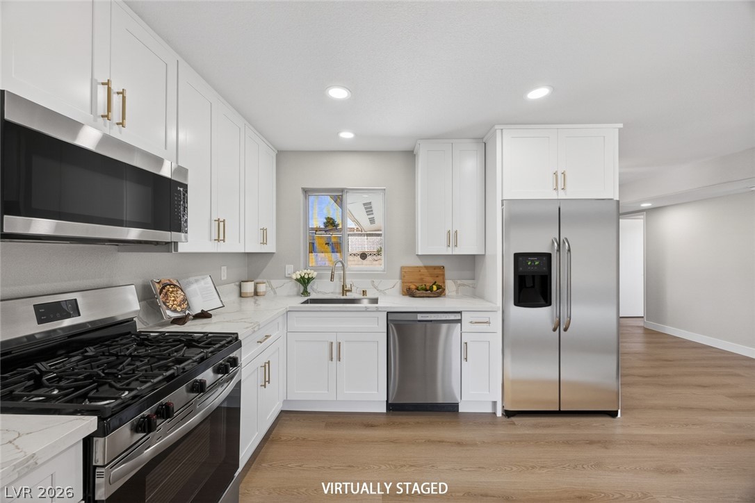 2484 Anglia Street Las Vegas, NV 89142 - Photo 4 of 20 This modern kitchen features crisp white cabinetry and essential stainless steel appliances.