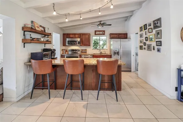 a dining area with stainless steel appliances kitchen island granite countertop a dining table and chairs in it