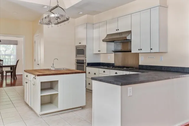 a kitchen with stainless steel appliances granite countertop a stove and a white cabinet