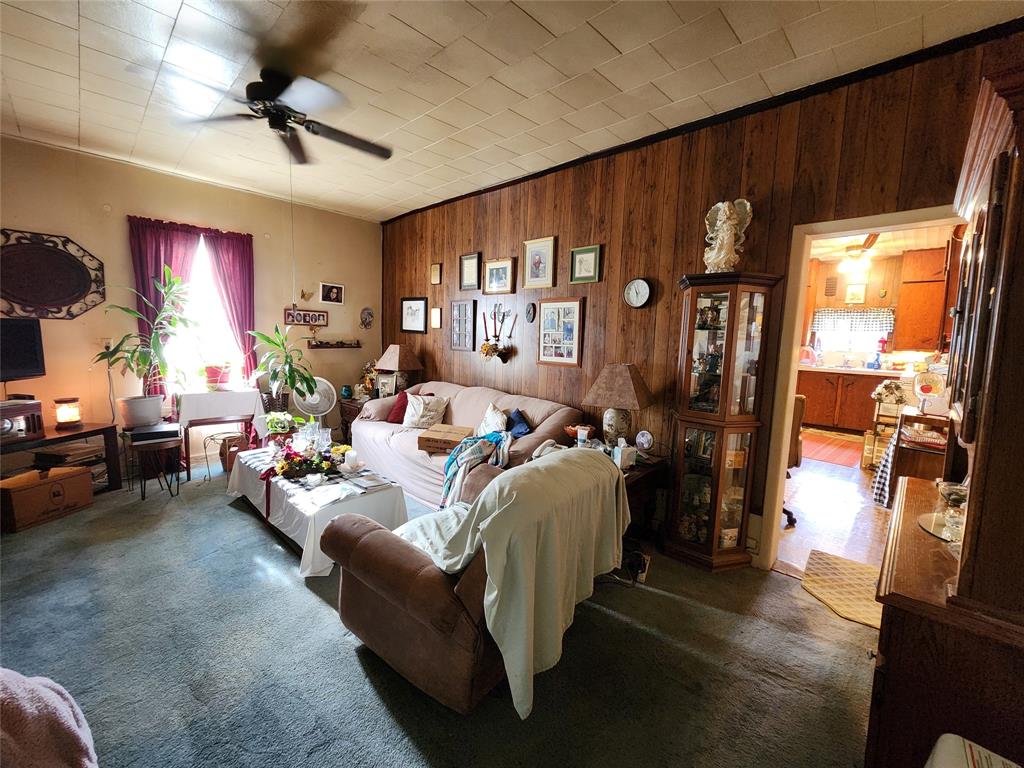 403 Barker Street Cumby, TX 75433 - Photo 6 of 16 Living area featuring wood-paneled accent wall, textured ceiling, and a ceiling fan