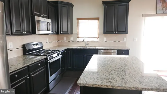 a kitchen with kitchen island granite countertop a sink stove and cabinets