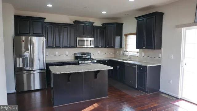 a kitchen with kitchen island granite countertop stainless steel appliances and wooden cabinets