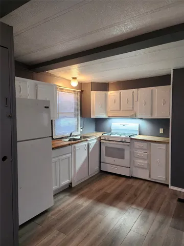 a kitchen with granite countertop white cabinets and white appliances