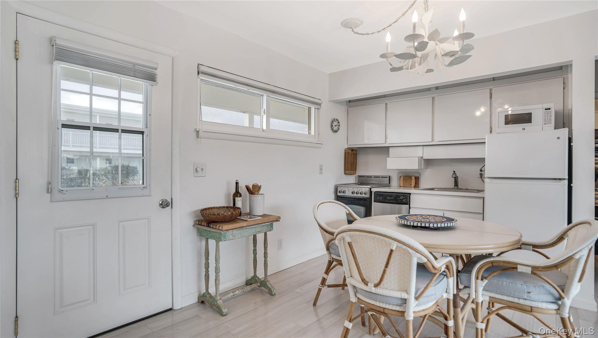 281 Dune Road, Unit 2A Westhampton Beach, NY 11978 - Photo 15 of 19 a kitchen with stainless steel appliances kitchen island granite countertop a refrigerator a stove a microwave oven with white cabinets and wooden floor
