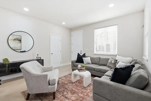 a living room with furniture a mirror a lamp and a window