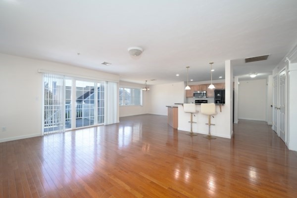 117 Tamarack Lane, Unit 117 Abington, MA 02351 - Photo 12 of 26 a view of an empty room with wooden floor and a kitchen