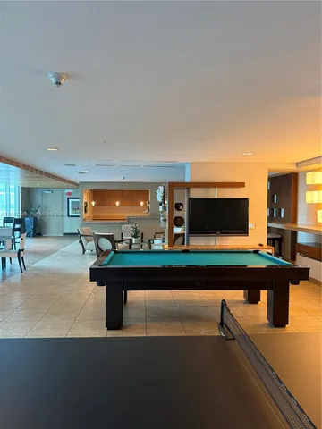 a living room with furniture pool table and flat screen tv