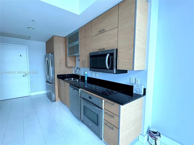 a kitchen with stainless steel appliances a sink and wooden cabinets