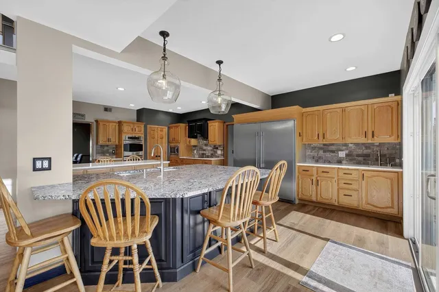 a kitchen with stainless steel appliances kitchen island granite countertop a table chairs sink and cabinets