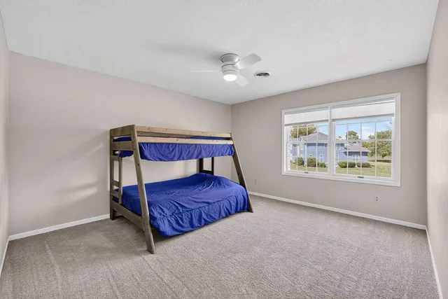 a bedroom with a bed flat screen tv and windows
