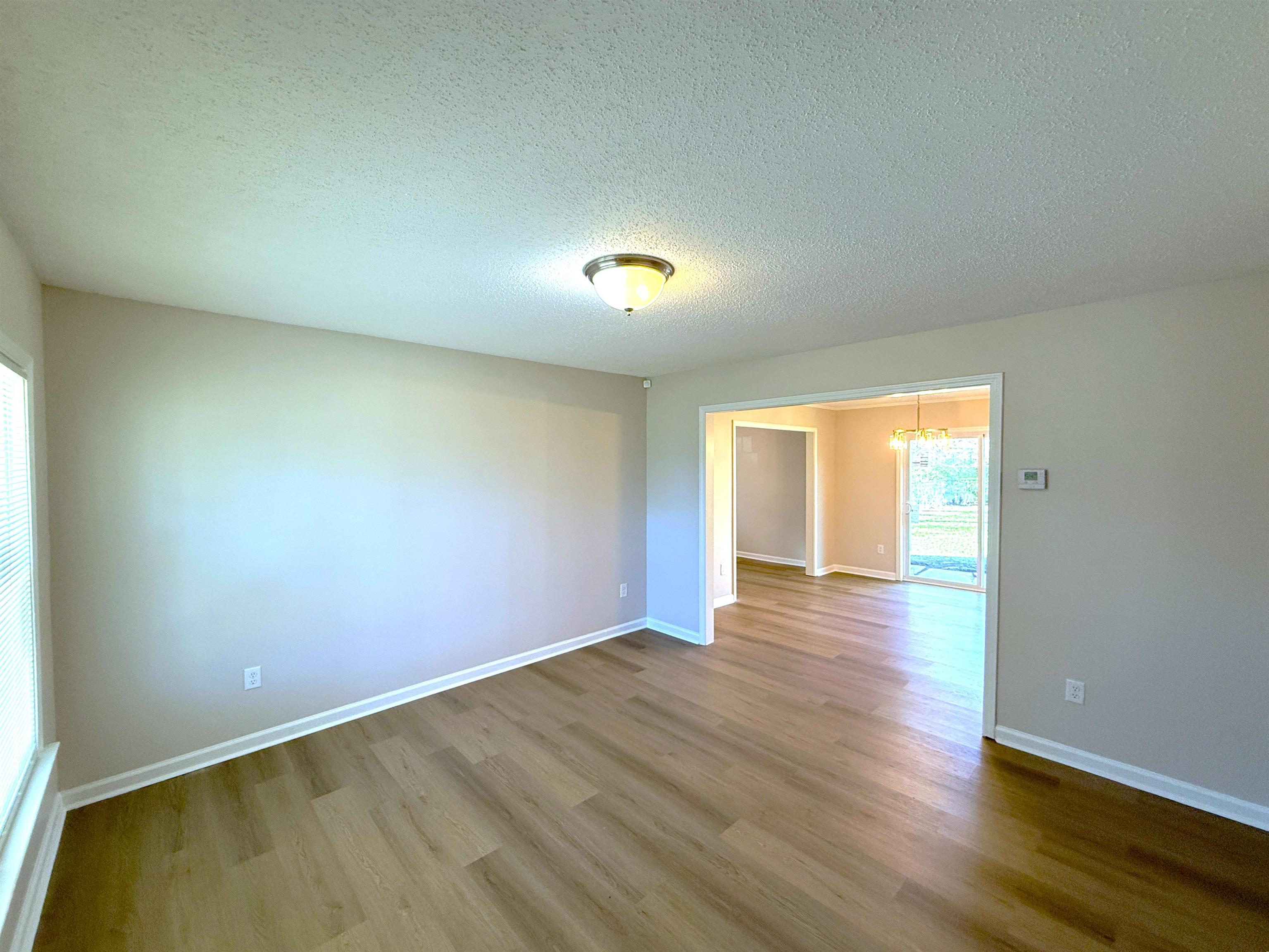 5165 Sea Shore Road Memphis, TN 38109 - Photo 3 of 20 Empty room featuring a textured ceiling, wood finished floors, and a chandelier