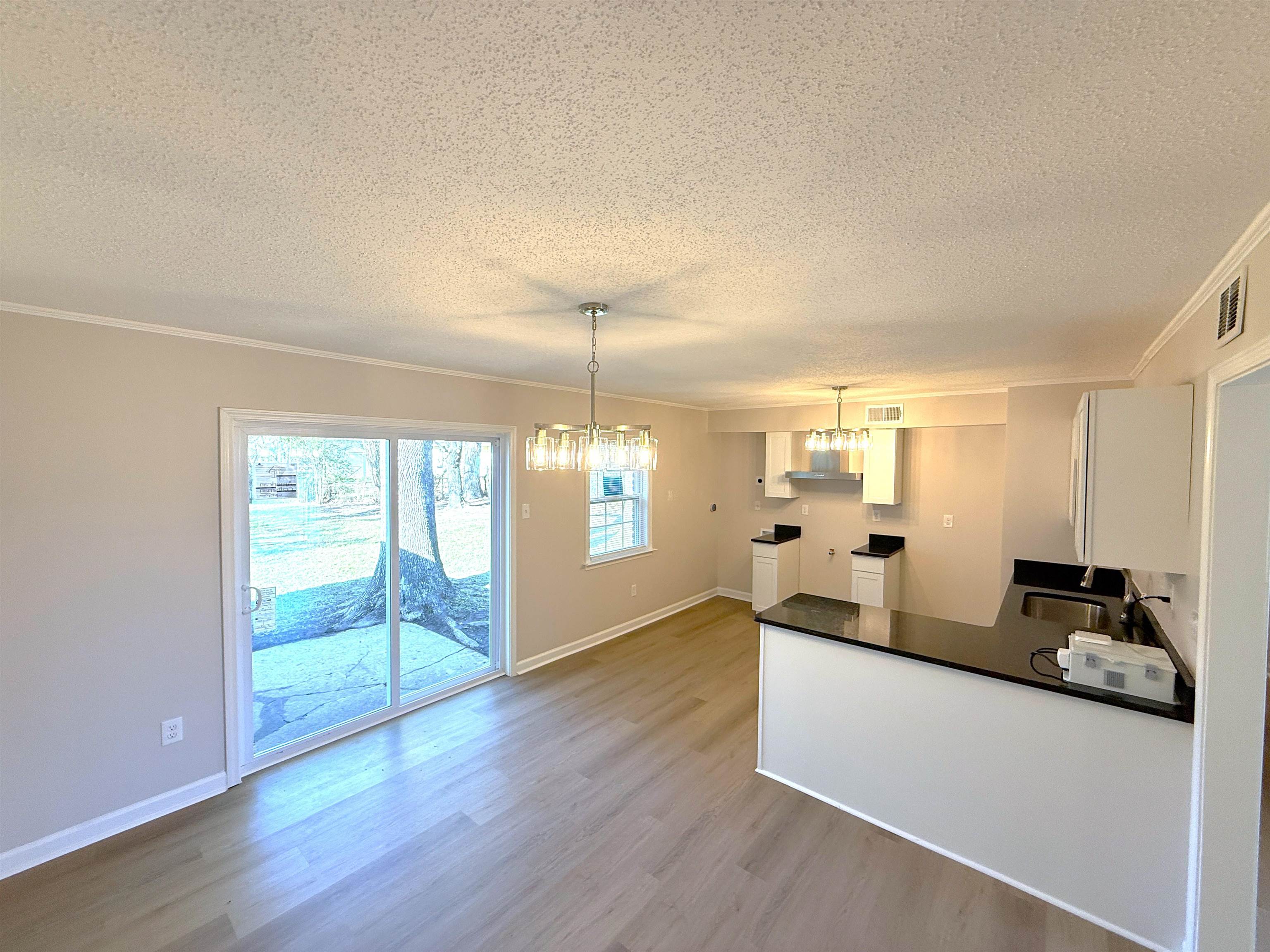 5165 Sea Shore Road Memphis, TN 38109 - Photo 4 of 20 Kitchen featuring dark countertops, a peninsula, crown molding, a chandelier, and pendant lighting