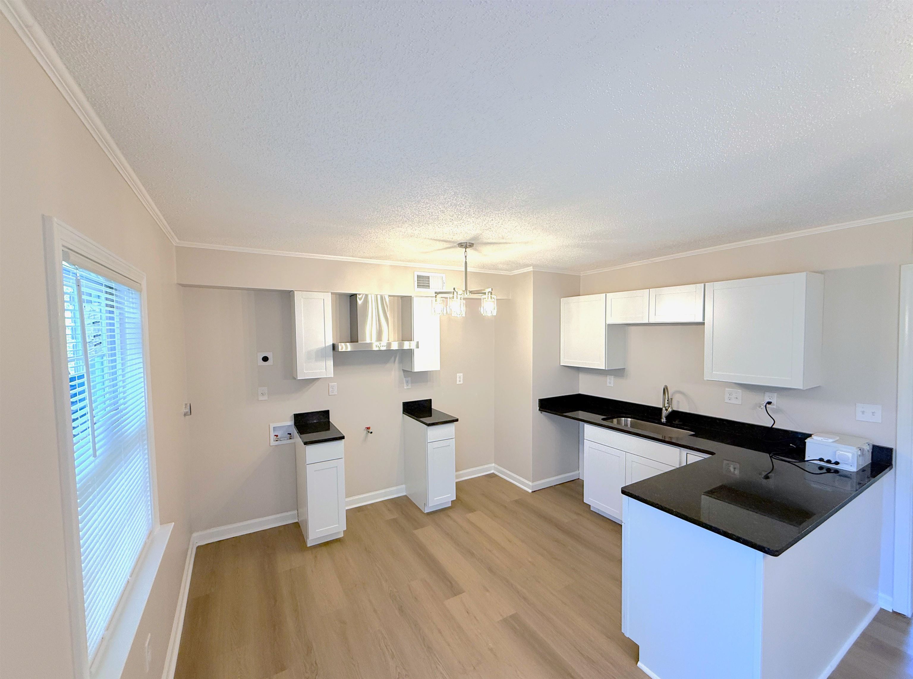 5165 Sea Shore Road Memphis, TN 38109 - Photo 5 of 20 Kitchen featuring white cabinetry, hanging light fixtures, a textured ceiling, crown molding, and a peninsula