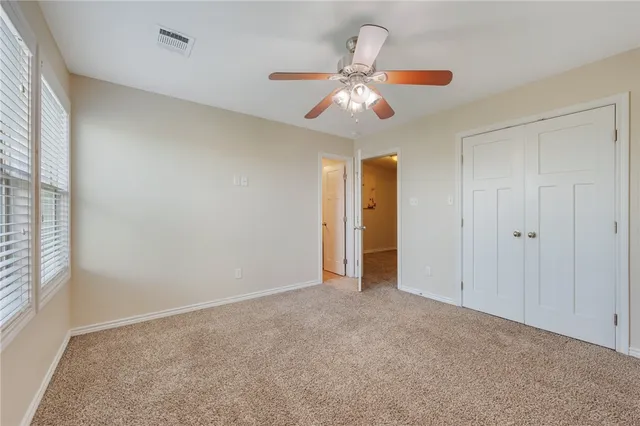 a view of an empty room and chandelier fan