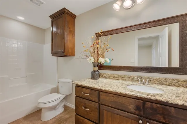 a bathroom with a granite countertop sink toilet and a mirror