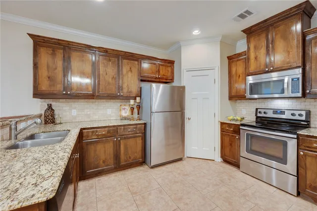 a kitchen with stainless steel appliances granite countertop a refrigerator stove top oven and sink