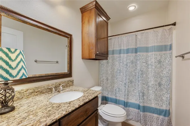 a bathroom with a granite countertop sink toilet a mirror and shower