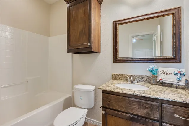 a bathroom with a granite countertop toilet a sink and bathtub