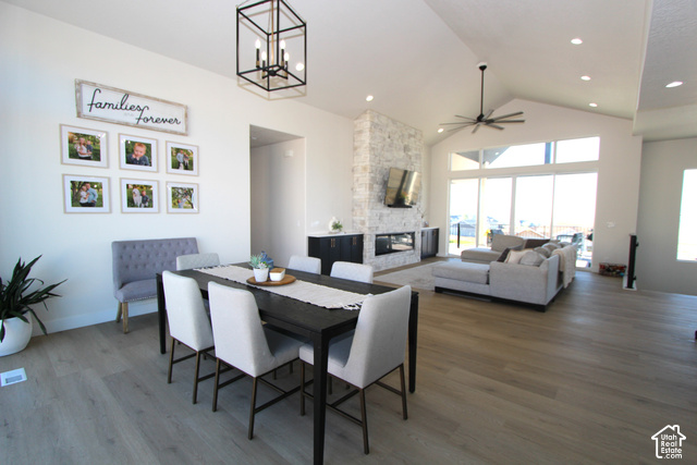 2201 East Unity Way Eagle Mountain, UT 84005 - Photo 9 of 39 Vaulted ceilings with recessed lighting, wood-finish flooring, full-height stone fireplace with a built-in media center, large format sliding glass doors, and a linear chandelier