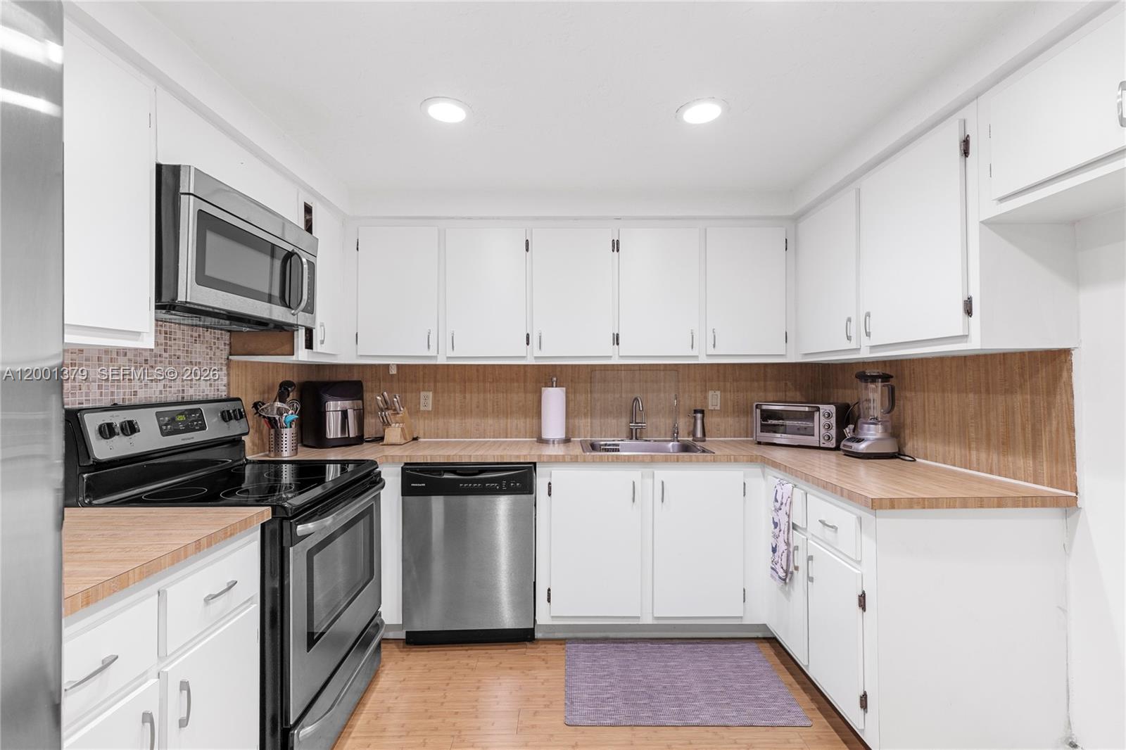 16251 Golf Club Road, Unit 311 Weston, FL 33326 - Photo 15 of 38 a kitchen with stainless steel appliances granite countertop grey cabinets a stove a sink and dishwasher with wooden floor