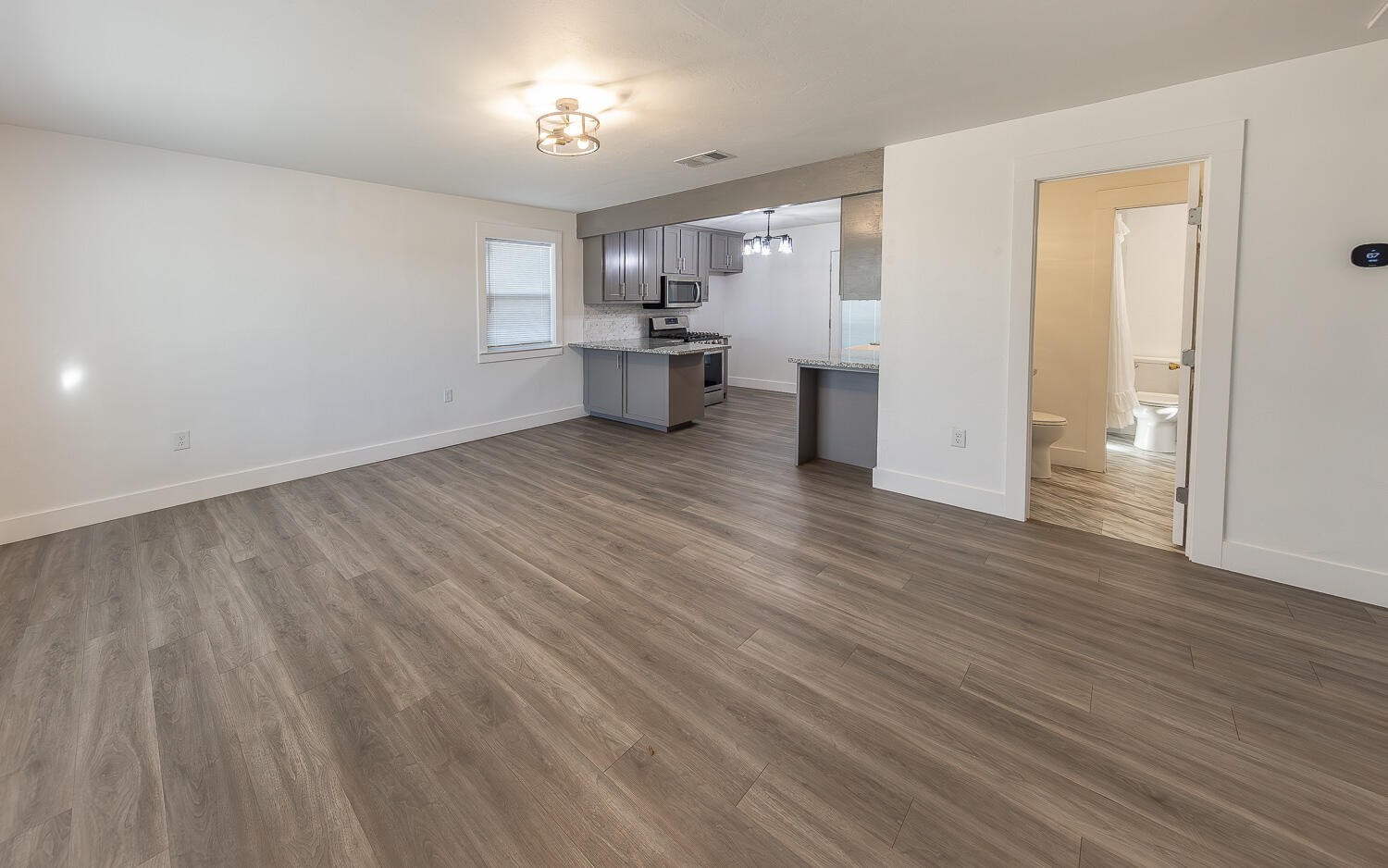 4816 40th Street Lubbock, TX 79414 - Photo 2 of 21 an empty room with wooden floor and a kitchen