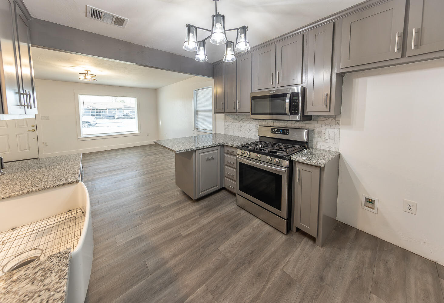 4816 40th Street Lubbock, TX 79414 - Photo 7 of 21 a large kitchen with stainless steel appliances granite countertop a stove a sink dishwasher and a microwave oven with wooden floor
