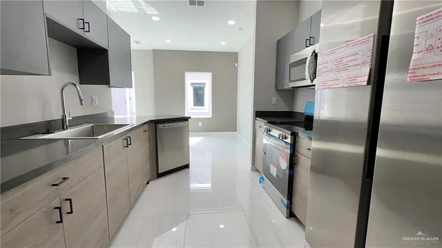 a kitchen with stainless steel appliances granite countertop a refrigerator a sink and a stove