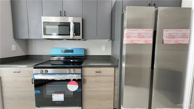 a kitchen with stainless steel appliances granite countertop a stove a microwave and a refrigerator