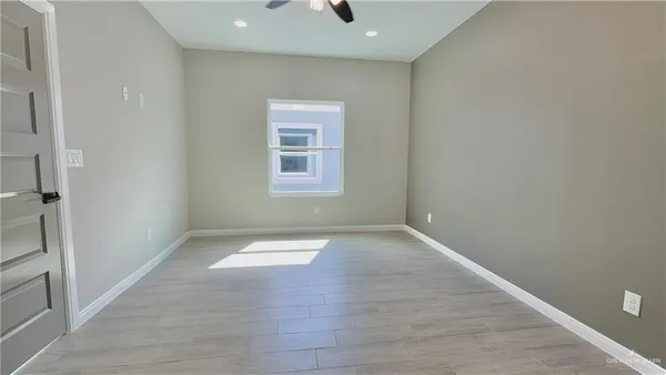 a view of an empty room with wooden floor and a window