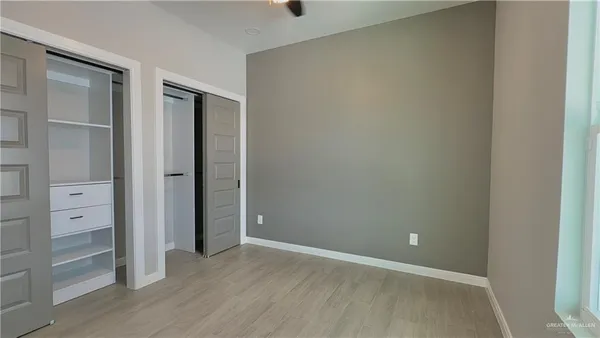 a view of an empty room with wooden floor and closet