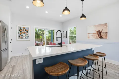 a kitchen with stainless steel appliances granite countertop a stove a sink a microwave a dining table and chairs with wooden floor