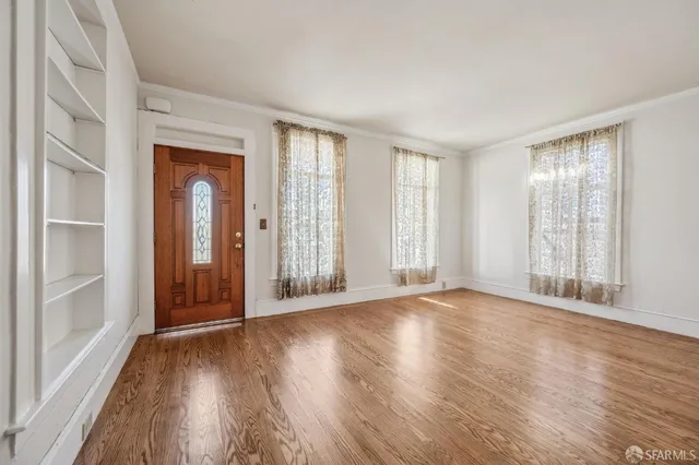 a view of an empty room with wooden floor and a window