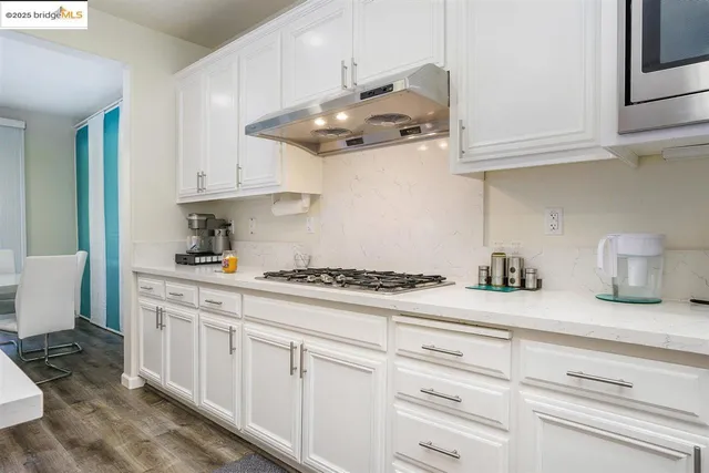 a kitchen with stainless steel appliances granite countertop white cabinets and a stove
