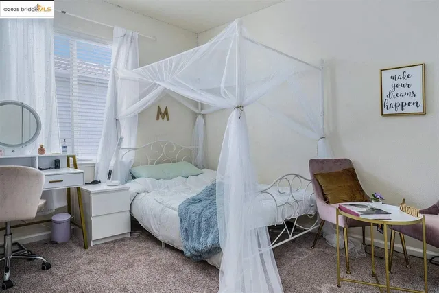a bedroom with a bed a desk and chair with wooden floor
