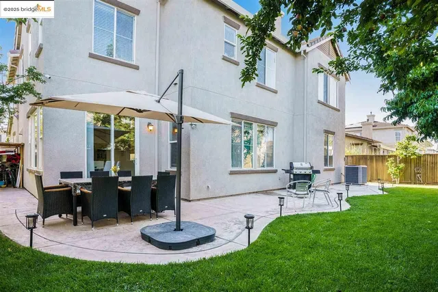 a view of a patio with table and chairs potted plants and a large tree
