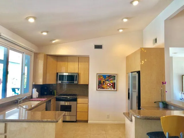 a kitchen with stainless steel appliances granite countertop a refrigerator a stove and a sink with wooden floor