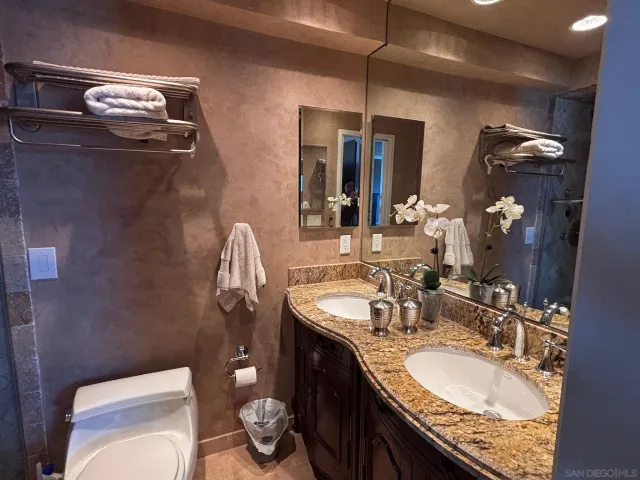 a bathroom with a granite countertop toilet sink and mirror