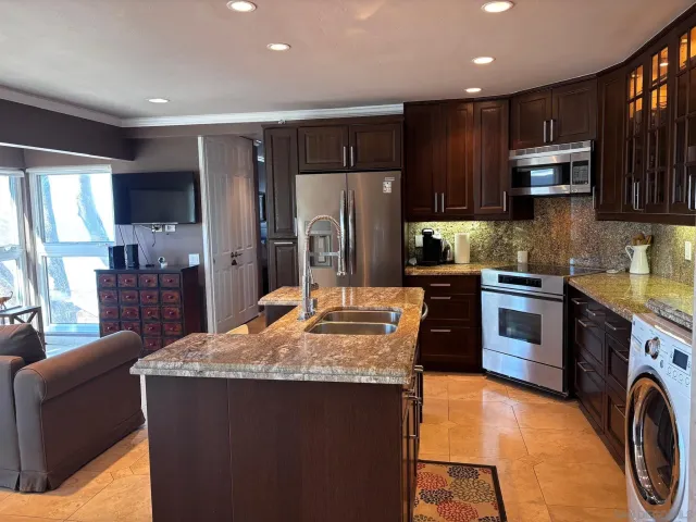 a kitchen with stainless steel appliances granite countertop a refrigerator a stove top oven a sink and dishwasher