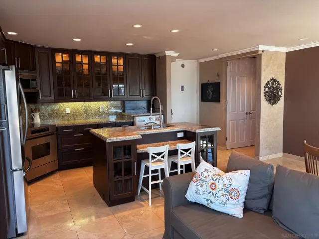 a kitchen with stainless steel appliances granite countertop a refrigerator a sink a stove a dining table and chairs