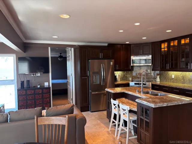 a kitchen with stainless steel appliances granite countertop a table chairs sink refrigerator and microwave