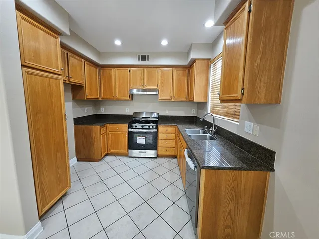 a kitchen with stainless steel appliances granite countertop a stove a sink and a refrigerator