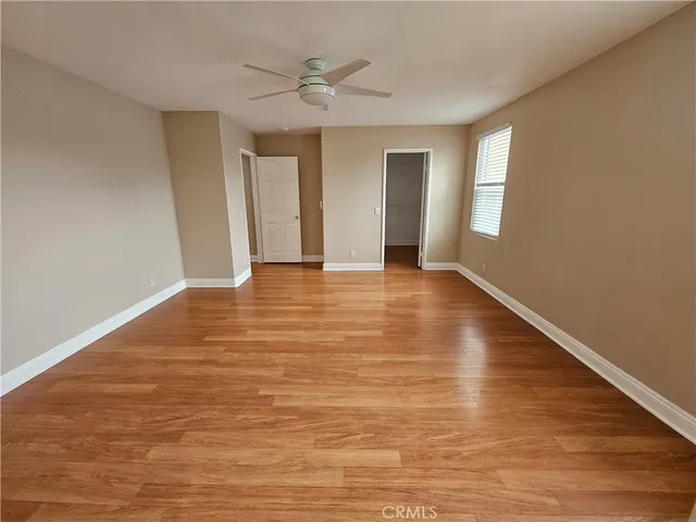 a view of an empty room with window and wooden floor