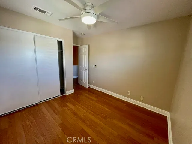 an empty room with a ceiling fan and wooden floor