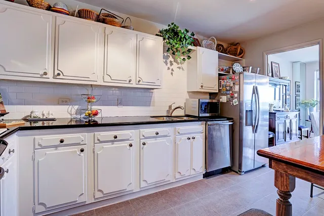 a kitchen with granite countertop white cabinets and refrigerator