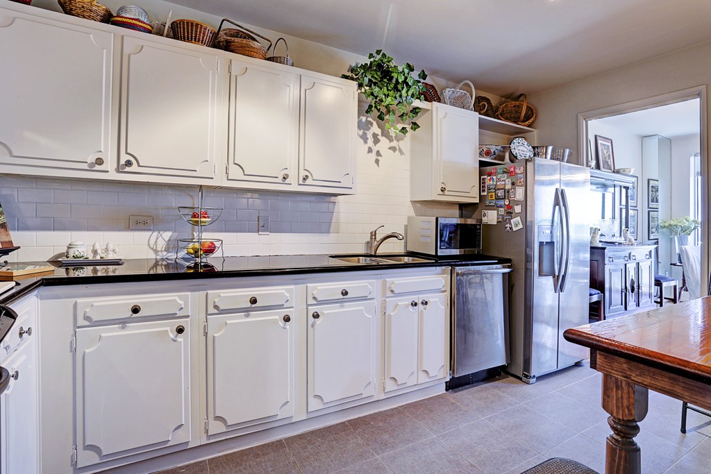 2200 Willowick Road, Unit 7B Houston, TX 77027 - Photo 14 of 32 a kitchen with granite countertop white cabinets and refrigerator