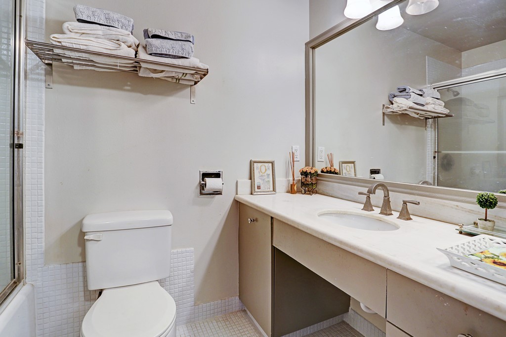 2200 Willowick Road, Unit 7B Houston, TX 77027 - Photo 21 of 32 a bathroom with a sink a toilet and mirror