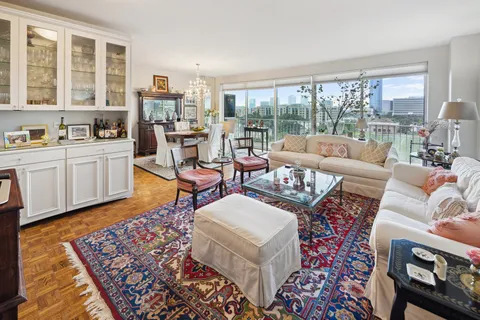 a living room with furniture floor to ceiling window and wooden floor