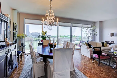 a view of a dining room with furniture a chandelier and large windows