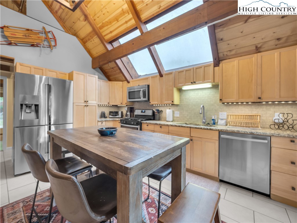 404 Charter Hills Road Beech Mountain, NC 28604 - Photo 9 of 36 a kitchen with stainless steel appliances a sink a stove a refrigerator cabinets and a dining table